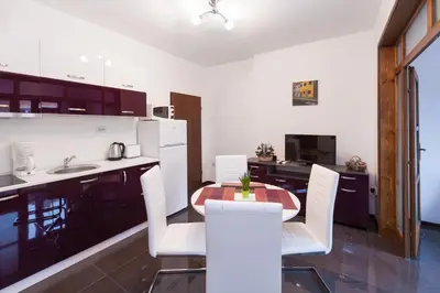 a kitchen with a table and white chairs in a kitchen at Central Beach GUEST ROOMS in Burgas City