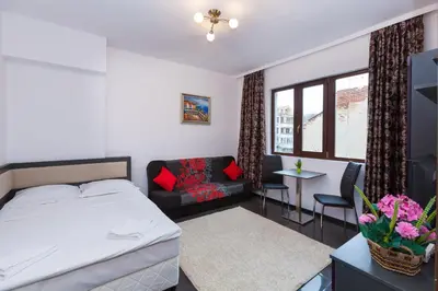 a bedroom with a bed and a couch and a table at Central Beach GUEST ROOMS in Burgas City