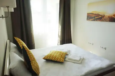 a white bed with yellow pillows on top of it at Super Central Luxury Apartments in Burgas City