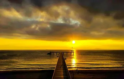 a pier with the sun setting over the ocean at Super Central Luxury Apartments in Burgas City