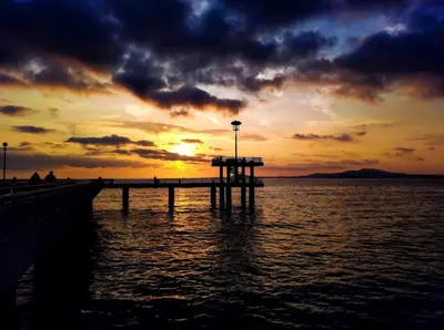 a pier on the water with a sunset in the background at Super Central Luxury Apartments in Burgas City