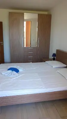 a large white bed with a blue pillow on it at Sea Bedroom Apartments in Nesebar