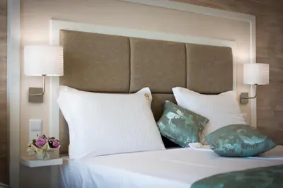 a white bed with two pillows and two lamps at Siena Palace in Primorsko