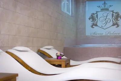 two beds in a room with a wall at Siena Palace in Primorsko