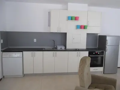 a kitchen with white cabinets and a sink and a chair at Apartment Sredna Gora in Burgas City
