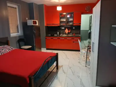 a kitchen with red cabinets and a red bed in a room at Studio Nera in Pomorie