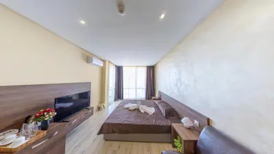 a large room with a bed and a flat screen tv at Aparthotel Paradiso in Nesebar