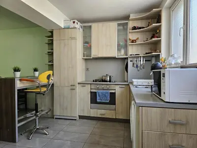 a kitchen with wooden cabinets and a desk in it at Family House Manolov in Obzor