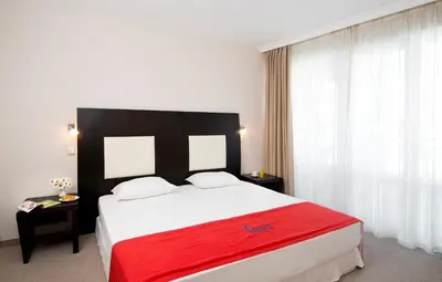 a bedroom with a large bed with a red blanket at Calypso Hotel - All Inclusive in Sunny Beach