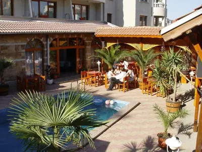 a group of people sitting at a restaurant next to a pool at Hotel Eos in Kiten