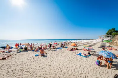 a group of people sitting on a beach at Riviera Fort Beach Apartments in Ravda