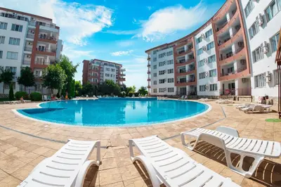 a swimming pool with lounge chairs and buildings at Riviera Fort Beach Apartments in Ravda