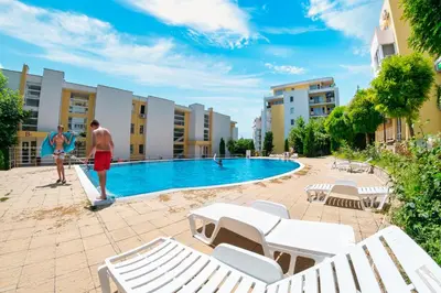 a man and a woman standing next to a swimming pool at Crown Fort Club in Sveti Vlas