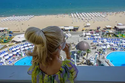 a woman looking out at a beach and the ocean at Imperial Palace Hotel in Sunny Beach