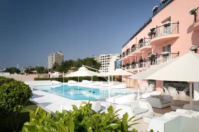 a pool with white chairs and umbrellas next to a building at Hotel Residence Dune - Free Beach Access in Sunny Beach