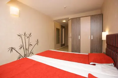 a bedroom with a red and white bed and a cabinet at Hotel Kotva - All Inclusive in Sunny Beach