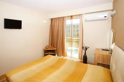 a bedroom with a yellow bed and a window at Hotel Kotva - All Inclusive in Sunny Beach