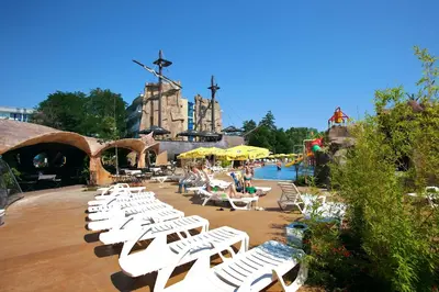 a group of white lounge chairs in front of a pool at Hotel Kotva - All Inclusive in Sunny Beach