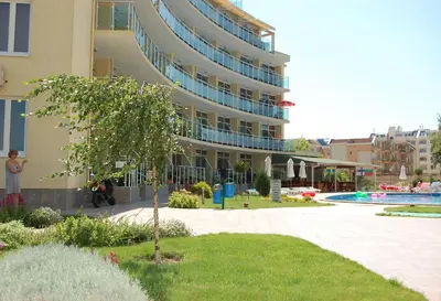 a large apartment building with a tree in front of it at Julia Family Apartments in Sunny Beach