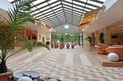 a lobby with a ceiling with skylights and chairs at Les Magnolias Hotel in Primorsko