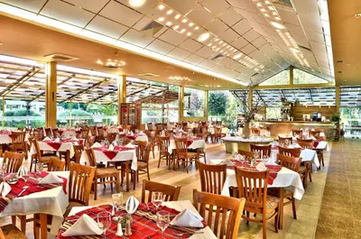 a dining room with tables and chairs in a restaurant at Les Magnolias Hotel in Primorsko