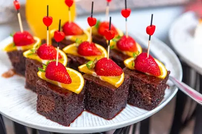 a plate of chocolate cakes with strawberries and oranges at Hotel Sunny in Sozopol