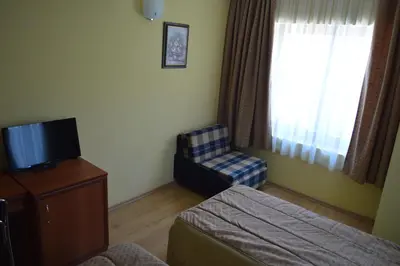 a hotel room with a bed and a tv and a chair at Stankoff Hotel in Nesebar
