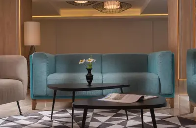 a living room with a blue couch and a table at Hotel Pomorie Sun - All Inclusive in Sunny Beach