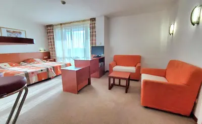 a room with a bedroom with a bed and a chair at Hotel Fenix - All Inclusive in Sunny Beach