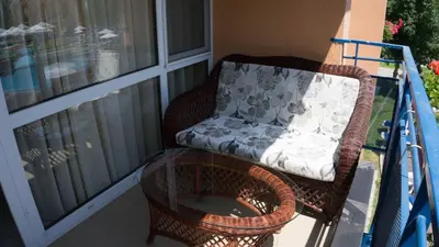 a wicker chair sitting on a balcony with a glass table at Elite Apartments in Sunny Beach