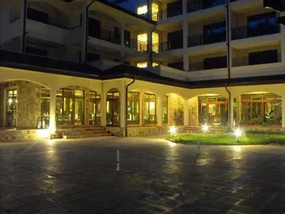 an empty parking lot in front of a building at night at Hotel Park in Karnobat