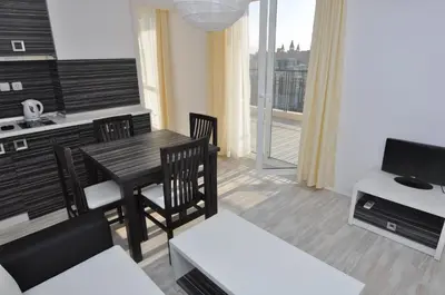 a living room with a table and chairs and a kitchen at Boutique Suites Rainbow 4 in Sunny Beach