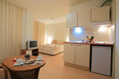 a kitchen and living room with a table and a room with a bed at Rainbow 2 Holiday Complex in Sunny Beach