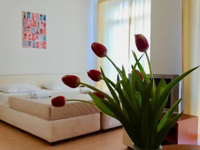 a bedroom with a bed and a vase with red flowers at Rainbow 2 Holiday Complex in Sunny Beach