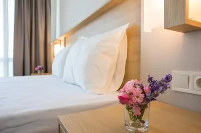 a bedroom with a bed with a vase of flowers on a table at Hotel Coop - Kiten in Kiten
