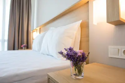a bedroom with a bed with a vase of flowers on a table at Hotel Coop - Kiten in Kiten