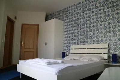 a bedroom with a white bed with a blue wall at Family Hotel Four Seasons Tsarevo in Tsarevo
