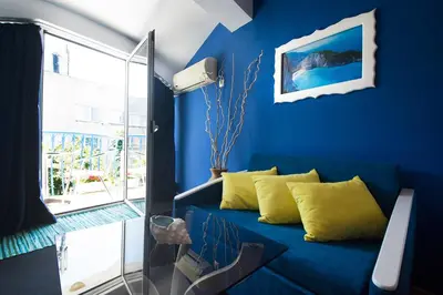 a blue room with a blue couch with yellow pillows at Family Hotel Four Seasons Tsarevo in Tsarevo