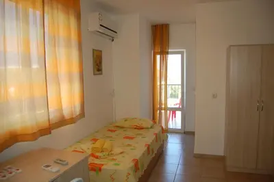a bedroom with a bed and a table and a window at Apartments Ivelin in Lozenets