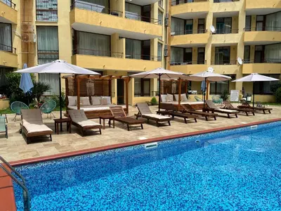 a swimming pool with chairs and umbrellas next to a building at Complex Sands Holiday Apartments in Sunny Beach