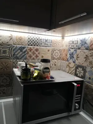 a microwave oven in a kitchen with tiles on the wall at Sea Garden Apartment IDM in Varna City