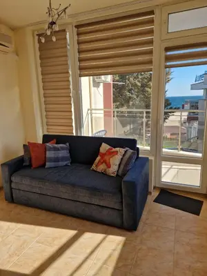 a blue couch in a room with a large window at Apartment Kalin complex Aurelia-RAVDA in Nesebar