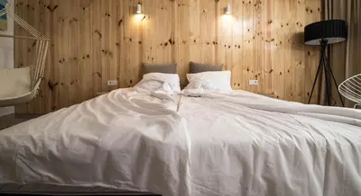 a large white bed in a room with wooden walls at The Poolhouse in Sunny Beach