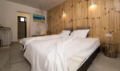 a bedroom with a large white bed with a wooden wall at The Poolhouse in Sunny Beach