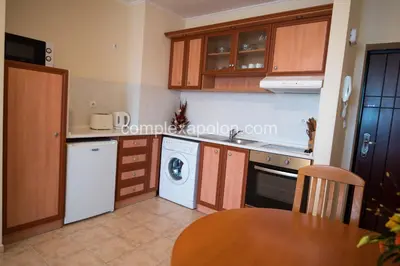 a kitchen with wooden cabinets and a wooden table at Complex Apolon in Nesebar