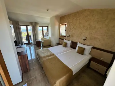 a bedroom with a large bed and a living room at Family Hotel Radiana in Sozopol