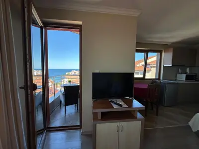 a living room with a television and a view of the ocean at Family Hotel Radiana in Sozopol