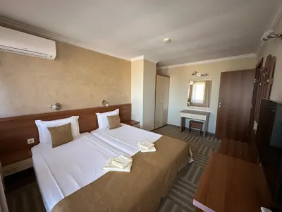 a hotel room with a large bed and a television at Family Hotel Radiana in Sozopol
