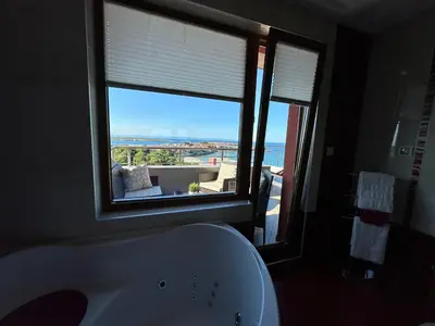 a bathroom with a white tub and a large window at Family Hotel Radiana in Sozopol