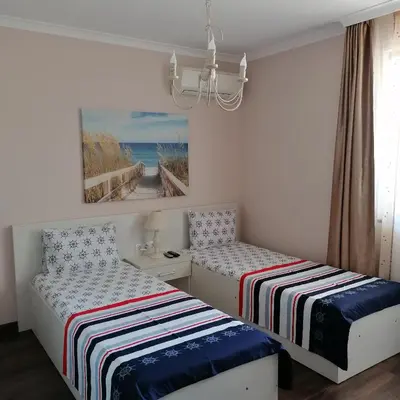 a bedroom with two beds and a chandelier at Apartments Dona in Chernomorets